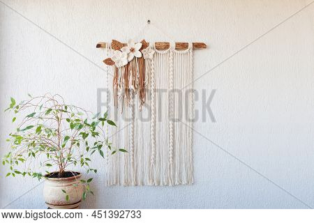 Handmade Macrame Wallhanging. 100% Cotton Wall Decoration With Wooden Stick Hanging On A White Wall.