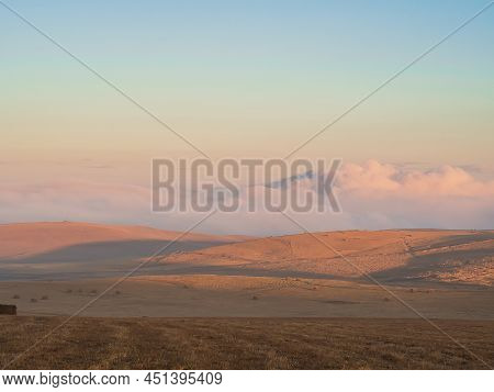 Alpine Autumn Fields Surrounded By Clouds Under A Blue Sky At Sunset
