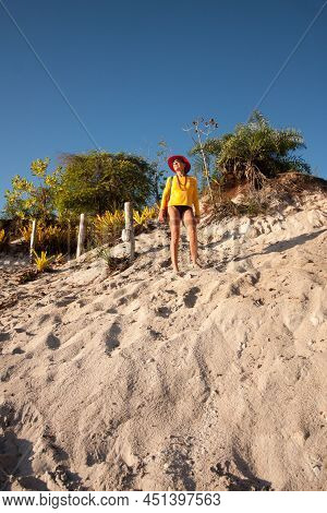 Lady Standing At The Top Of A Sand Dune At The River Beach Called Prianha In Caraiva, Bahia, Brazil