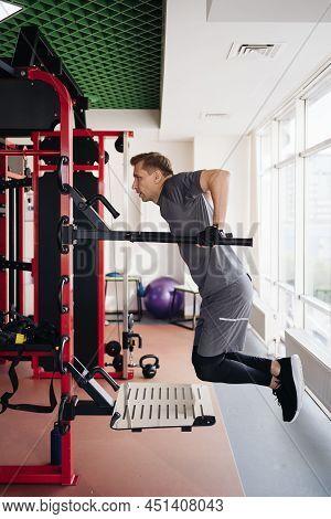 Athlete Man In The Gym Doing Elevations. Caucasian Male Training In The Gym During The Day