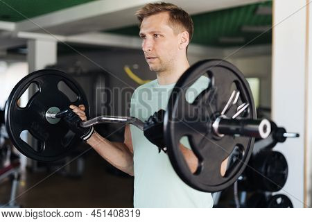 Athlete Man Lifting Barbells Working Out With Curl Bar In The Gym Doing Elevations. Caucasian Male T