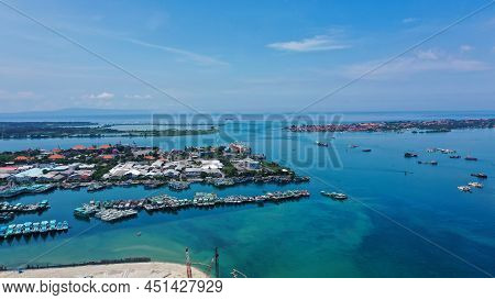 Aerial Of Beach, Pier, Boats, Resort And Businesses On Tip Of Tanyung Benoa Peninsula Above Dark Blu