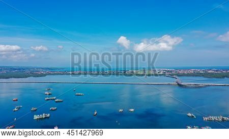 Aerial Of Beach, Pier, Boats, Resort And Businesses On Tip Of Tanyung Benoa Peninsula Above Dark Blu