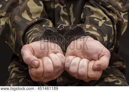 A Military Soldier In Handcuffs, Hands Behind His Back, On A Dark Background. Concept: War Criminal,