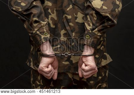 A Military Man In Camouflage Is Handcuffed On A Dark Background. Concept: War Criminal, Prisoner Of 