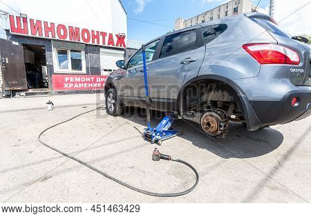 Samara, Russia - July 4, 2021: Сar At The Tire Mounting With Removed Wheel On Pneumatic Jack. Season