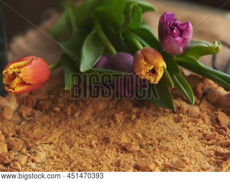 Homemade Cake Sprinkled With Cookie Crumbs On A Metal Vintage Dish, Decorated With Tulips. Food Back