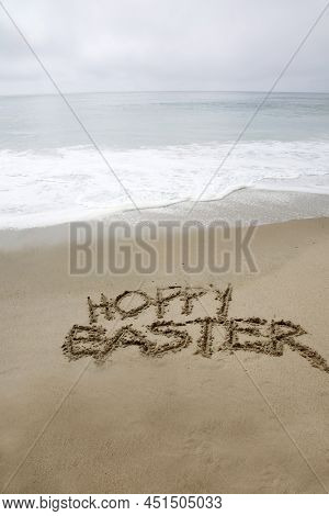 Hoppy Easter. The words HOPPY EASTER written in the sand by the ocean. Easter Sunday is a day to celebrate at the beach or anywhere you like. Hoppy Easter to all. 