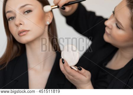 Professional Make-up Artist Applying Powder Rouge With Domed Powder Brush To Cheekbone Of Young Good