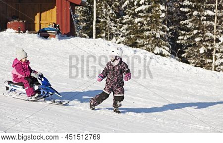 Umea, Norrland Sweden - February 19, 2022: Two Children Go Sledding On A Ski Slope