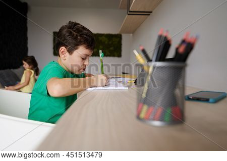 Handsome Clever Preadolescent Boy Doing His Homework. Concentrated Schoolboy Studying At Home. Inter