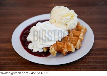 A Hot Waffle With Cherries, Ice Cream And Whipped Cream.