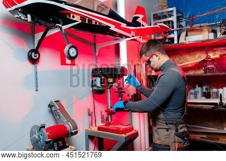 Young Male Engineer Or Technician Using Drill For Drone Details In Lab. Aircraft Capable Of Gps Surv