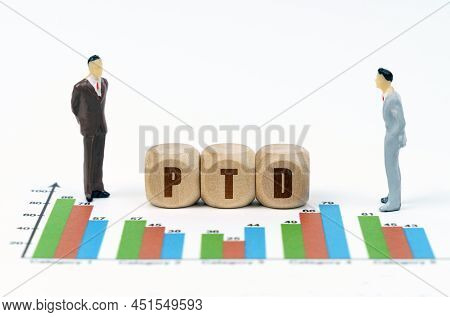 On Financial Reports With Graphs, A Figure Of Businessmen And Wooden Cubes With The Inscription - Pt