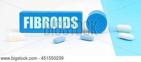 Medical Concept. On A White And Blue Surface Are Pills, A Stethoscope, A Pen And A Wooden Sign With 