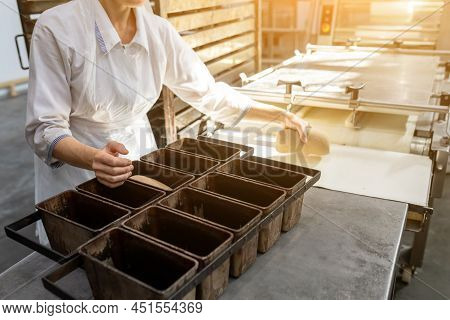 The Baker Fills A Baking Dish With Dough. Bread Production Stage In A Small Bakery