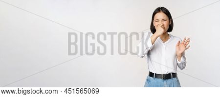 Disgusted Asian Girl Close Nose And Showing Rejection Gesture, Digusting Bad Smell, Standing Over Wh