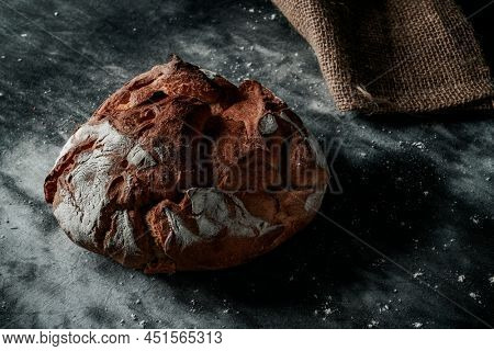 closeup of a round kamut wheat bread loaf on a mottled dark gray fabric surface