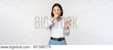 Disgusted Asian Girl Close Nose And Showing Rejection Gesture, Digusting Bad Smell, Standing Over Wh