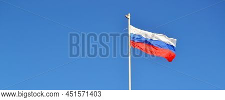 Banner, The Flag Of Russia Is Flying In The Wind Against The Blue Sky