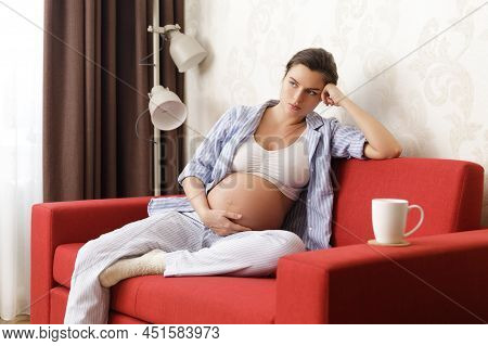 Tired Pregnant Woman Sitting With On The Red Sofa