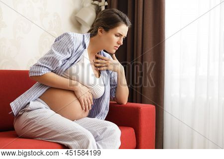 Young And Pregnant Woman At Home Feels Sick
