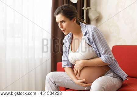 Young And Pregnant Woman At Home Feels Sick