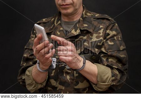 A Military Man In Handcuffs Makes A Phone Call On A Dark Background, Selective Focus. Concept: Priso