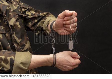 A Military Man In Handcuffs Holds An Army Badge In His Hand On A Dark Background, Selective Focus 35