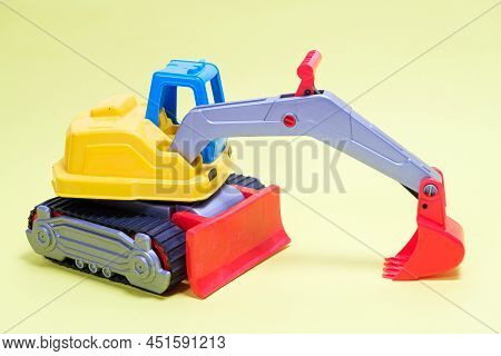 Plastic Excavator Car On Yellow Background. Construction Machinery Car For Digging For Toy Store And
