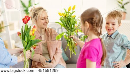 Cute Cildren Giving The Bunches Their Beautiful Mother. Concept Of The Family Relationship And Mothe