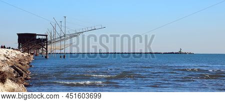 Fishing Huts On The Long Dam And Large Nets For Catching Fish And Crustaceans With The Blue Sea