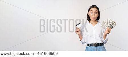 Finance And Money Concept. Happy Young Asian Woman Dancing With Cash And Credit Card, Smiling Please