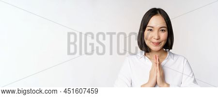 Close Up Portrait Of Young Japanese Woman Showing Namaste, Thank You Arigatou Gesture, Standing Over