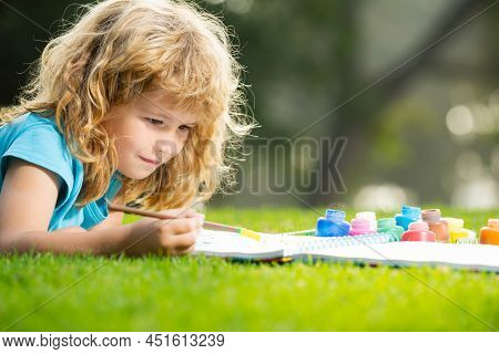Child Boy Enjoying Art And Craft Drawing In Backyard Or Spring Park. Children Drawing Draw With Penc