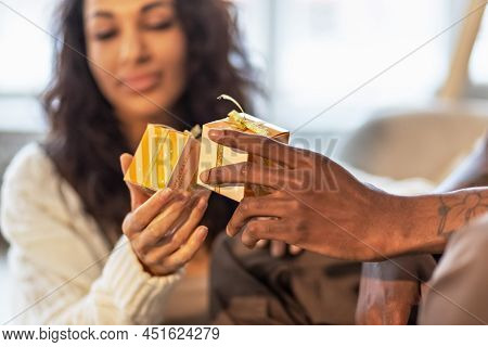 A Happy Couple Of Mulattoes Exchange Gifts With Each Other. Celebrating Joint Family Events.