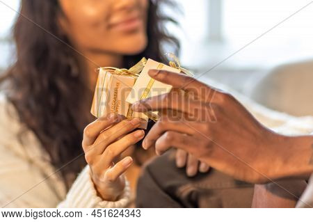 A Happy Couple Of Mulattoes Exchange Gifts With Each Other. Celebrating Joint Family Events.
