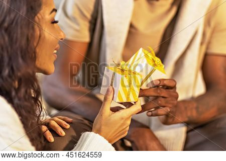 A Happy Couple Of Mulattoes Exchange Gifts With Each Other. Celebrating Joint Family Events.