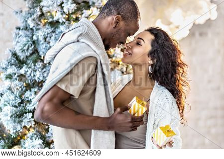 A Happy Couple Of Mulattoes Exchange Gifts With Each Other. Celebrating Joint Family Events