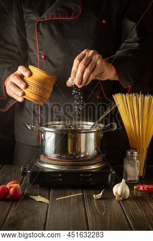 Cooking Delicious Soup For Lunch. Working Environment In The Kitchen. The Chef Adds Salt To The Stoc
