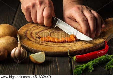 Slicing Carrots On A Wooden Board For Cooking. Professional Chef Hands With A Knife While Working On