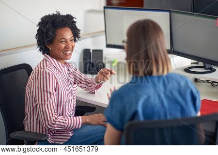 Two multiethinc female coworkers consulting together in the office working on the project