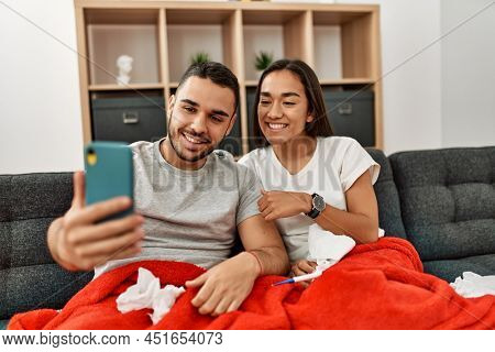Young latin ill couple having medical teleconsultation using smartphone at home.