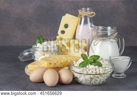 Dairy Products, Milk, Yogurt, Sour Cream, Several Types Of Cheese, Curd And Eggs On Dark Gray Table