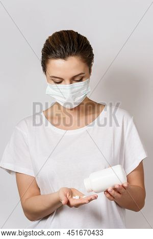Woman Wearing Face Mask Is Holding A White Pills