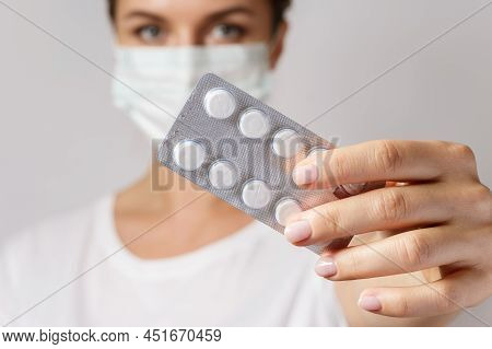Woman Wearing Face Mask Is Holding A White Pills