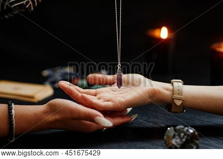 Side View Closeup Of Fortune Teller Holding Magic Crystal Over Palm Of Young Woman And Reading Her D