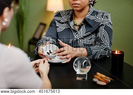 Close Up Of Fortune Teller Reading Coffee Grounds Telling Destiny In Seance With Young Woman, Copy S