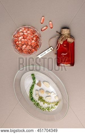 Jelatin Capsules, Algae Oil In Glass Bottle And Seaweed In Water In Transparent Plate On Brown Paper
