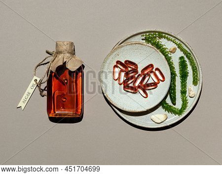 Glass Bottle With Algae Oil, Jelatin Capsules And Live Seaweed In Clay Plates. Transparent Container